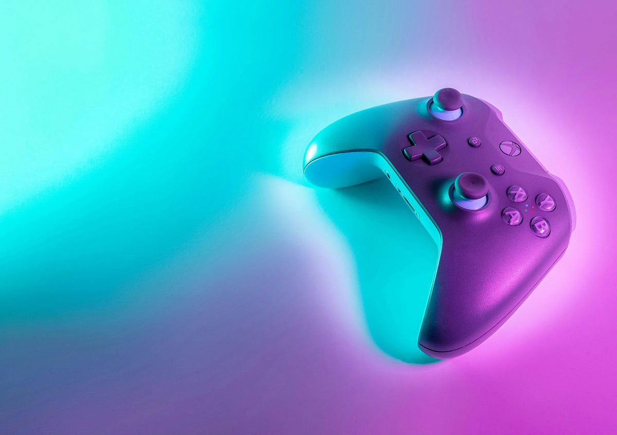 Xbox controller lit by cyan and magenta neon light